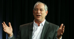 Foto de Ciro Gomes com cara de surpresa, os braços formam um angulo de 90° e ele usa um terno cinza.