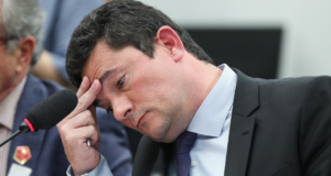 Foto de Sergio Moro preoupado com a cabeça deixada pra lateral apoiada na mão direita