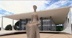 Imagem da frente do prédio do STF, com a estátua da justiça na frente.