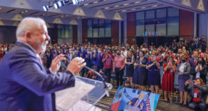 Lula sobre guerra na Ucrânia: “baixem as armas”. Foto do presidente durante live na Cidade do México. Ele está desfocado e a câmera mostra o público