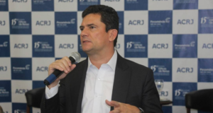 Foto de Sergio Moro, usando terno preto e falando ao microfone, durante um evento.