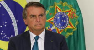 Bolsonaro tem expressão séria, desmotivante, usa terno preto e olhar fixo.