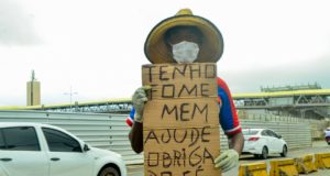 Imagem de um homem com um cartaz dizendo que tem fome; Brasil foi mal no ranking de país mais feliz do mundo