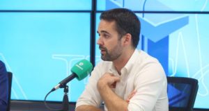 Foto de Eduardo Leite flando ao microfone em uma entrevista de rádio.