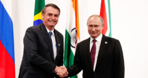 Foto de Bolsonaro sorrindo com aperto de mão em Vladimir Putin, presidente russo.