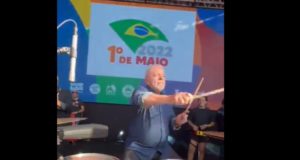 Lula está sentando em uma cadeira enquanto toca a bateria no Pacaembu.