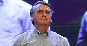 Jair Bolsonaro com expressão séria, vestindo camisa social azul