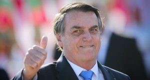 Jair Bolsonaro de terno e gravata fazendo sinal de ok e cara de aprovação