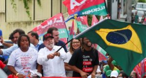 Lula em campanha no Complexo do Alemão, balançando bandeira do Brasil