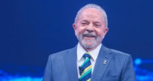 Lula sorrindo, usando terno e gravata