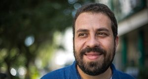 Boulos de camisa polo azul, olhando para o lado e sorrindo