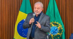 Lula discursando com bandeira do Brasil ao fundo