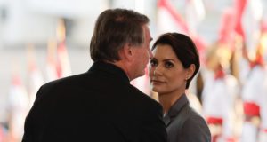 Michelle Bolsonaro olhando para Jair Bolsonaro, que está de costas