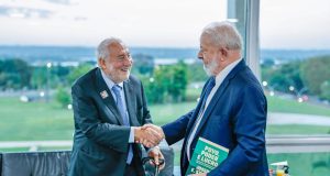 Lula e Stiglitz em aperto de mãos, os dois sorrindo e com trajes formais