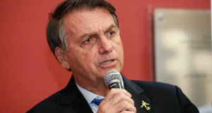 Jair Bolsonaro falando com expressão séria em fundo vermelho