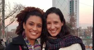 Marielle Franco e Monica Benicio posando lado a lado para foto, as duas sorrindo e com roupas de frio