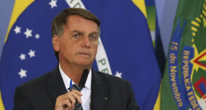 Jair Bolsonaro falando em microfone com expressão desconfiada