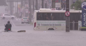 Cruzamento entre as avenidas Dom Pedro II e Coremas, no Centro de João Pessoa, alagado, com ônibus e moto passando em sentidos diferentes