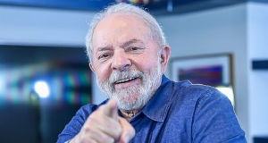 Lula de camisa jeans, sorrindo e apontando para a câmera