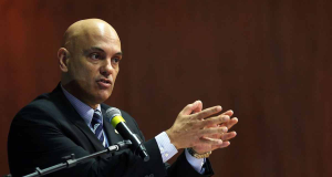 Alexandre de Moraes no canto esquerdo da foto, falando em microfone e gesticulando