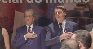 Valdemar Costa Neto e Jair Bolsonaro sérios, em pé, lado a lado, com a mão no peito