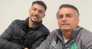 Jair Renan e o pai, o ex-presidente Jair Bolsonaro, posando para foto com sorrisos tímidos e roupa escura