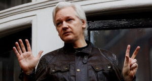 Julian Assange de roupa escura, sério, gesticulando