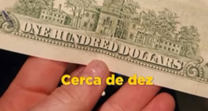 Mão segurando nota de cem dólares com legenda amarela escrito "Cerca de 10"