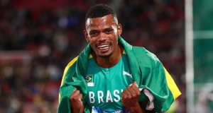 Fernando "Balotelli", do decatlo, sorrindo e comemorando, com uniforme e bandeira do Brasil