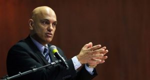 Alexandre de Moraes falando em microfone e gesticulando, sério