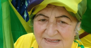 Maria de Fátima Mendonça Jacinto, conhecida como “Fátima de Tubarão”, vestida com as cores da bandeira do Brasil, sem sorrir, olhando para a câmera, em close