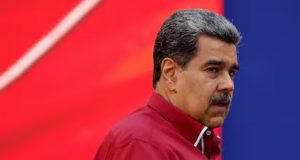 Nicolás Maduro com expressão desconfiada, de perfil, de roupa vinho