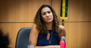 Anielle Franco de cabelo solto e camiseta azul marinho, com expressão de tédio